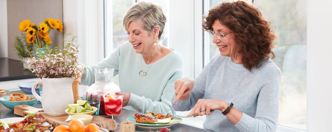 2 femmes d'une cinquantaine d'années en train de manger à table