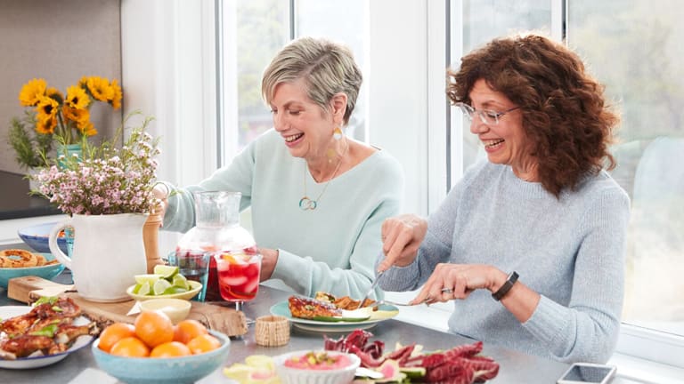 2 Frauen in ihrern Fünfzigern beim Essen am Tisch