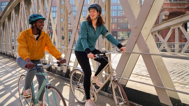 Zwei Frauen fahren gemeinsam Fahrrad.