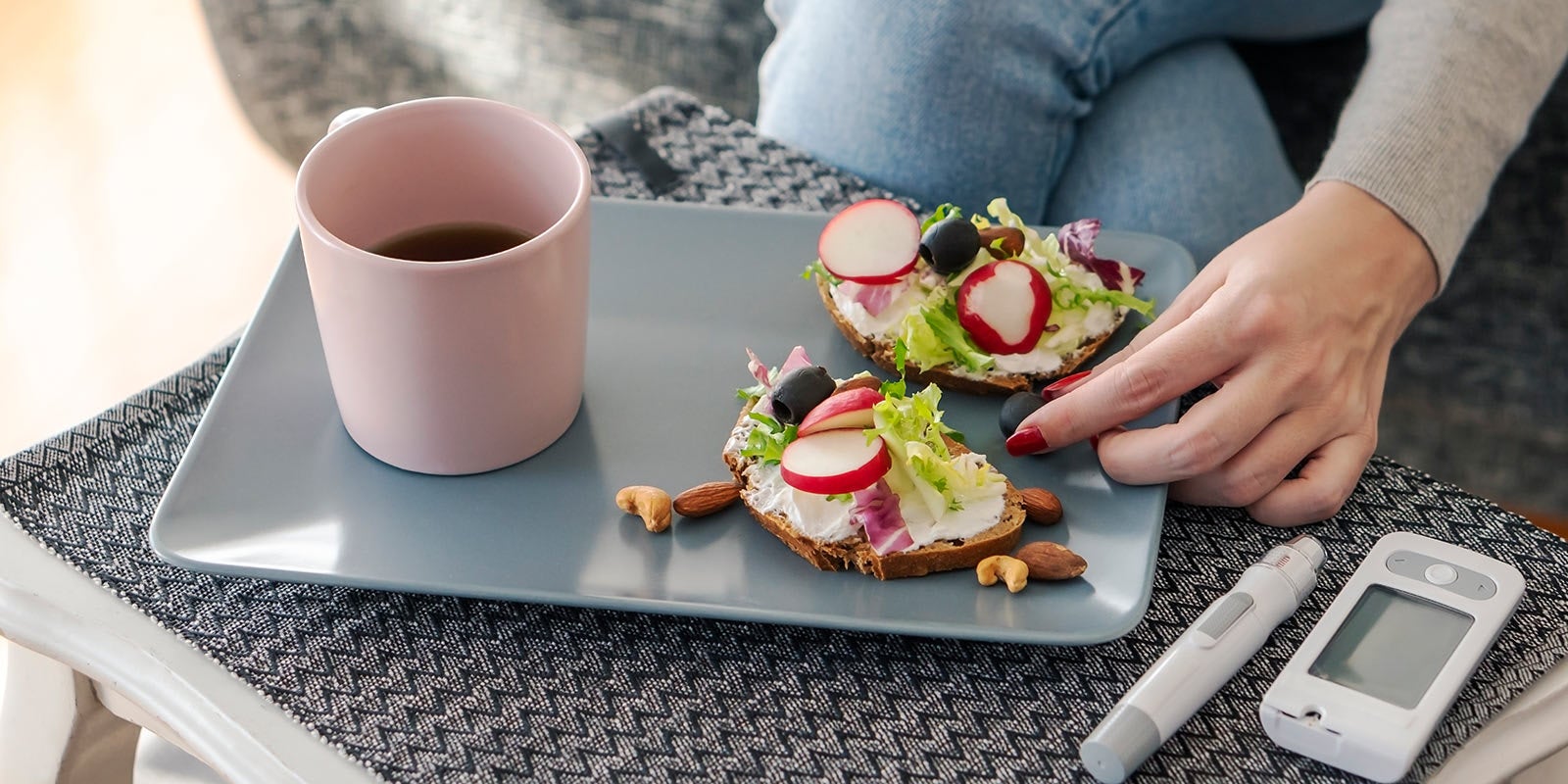 Ein Frühstücksteller mit belegtem Brot und Kaffee, daneben liegt das Blutzuckermessgerät.