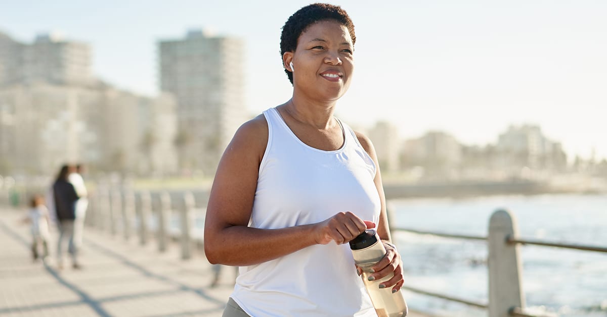 woman jogging at the waterfront with water bottle