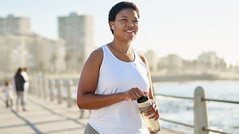 woman jogging at the waterfront with water bottle