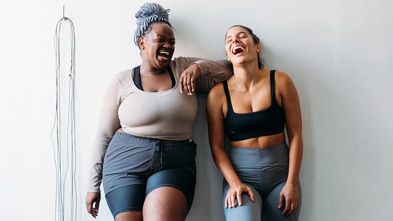  Two women laughing after a workout class. 