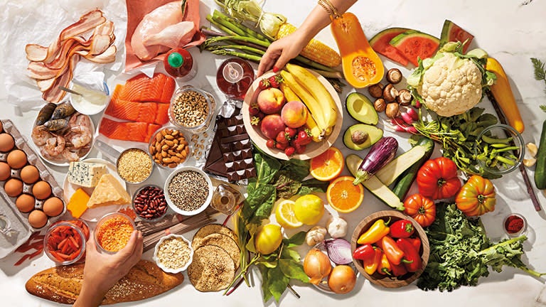 Ein Tisch ist gedeckt mit vielen ZeroPoint Lebensmitteln wie frischen Früchten, Gemüse, Fisch, Eiern etc.