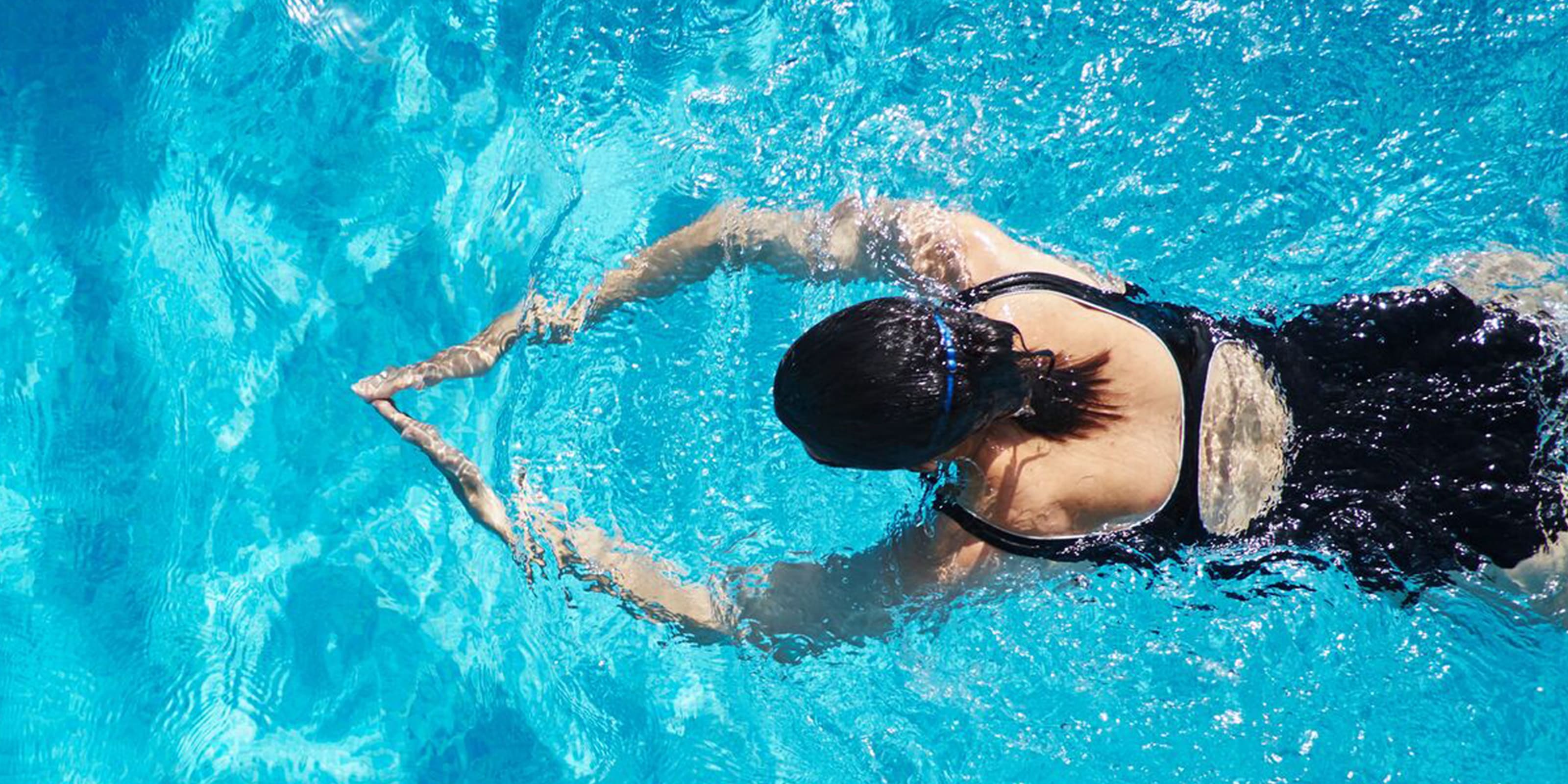 Frau in Badeanzug trainiert Brustschwimmen.