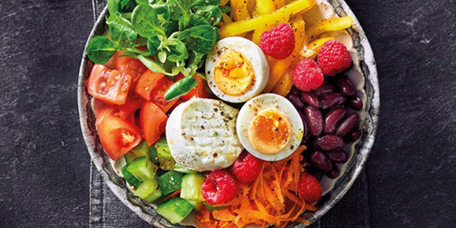 Eine Bowl mit frischem Gemüse, Huelsenfruechten, Käse und Ei