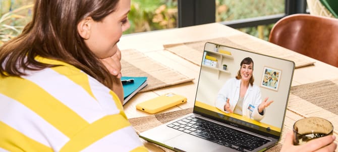 Woman having telehealth consultation with clinician on a laptop from her kitchen.