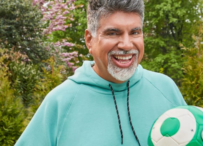WeightWatchers member August in a hoody, holding a volleyball and smiling at the viewer.