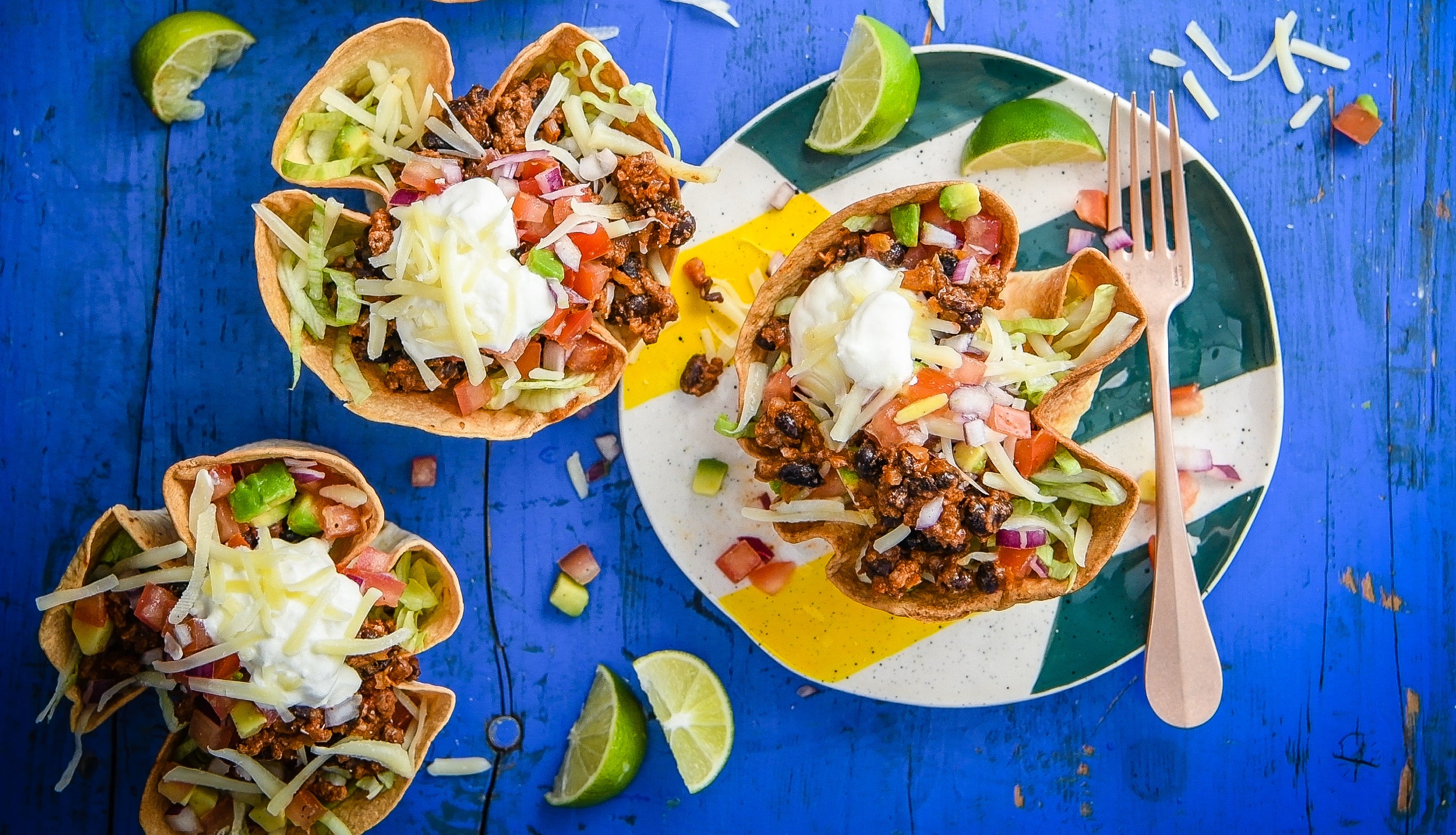 Beef tacos on plates alongside fresh tortillas.