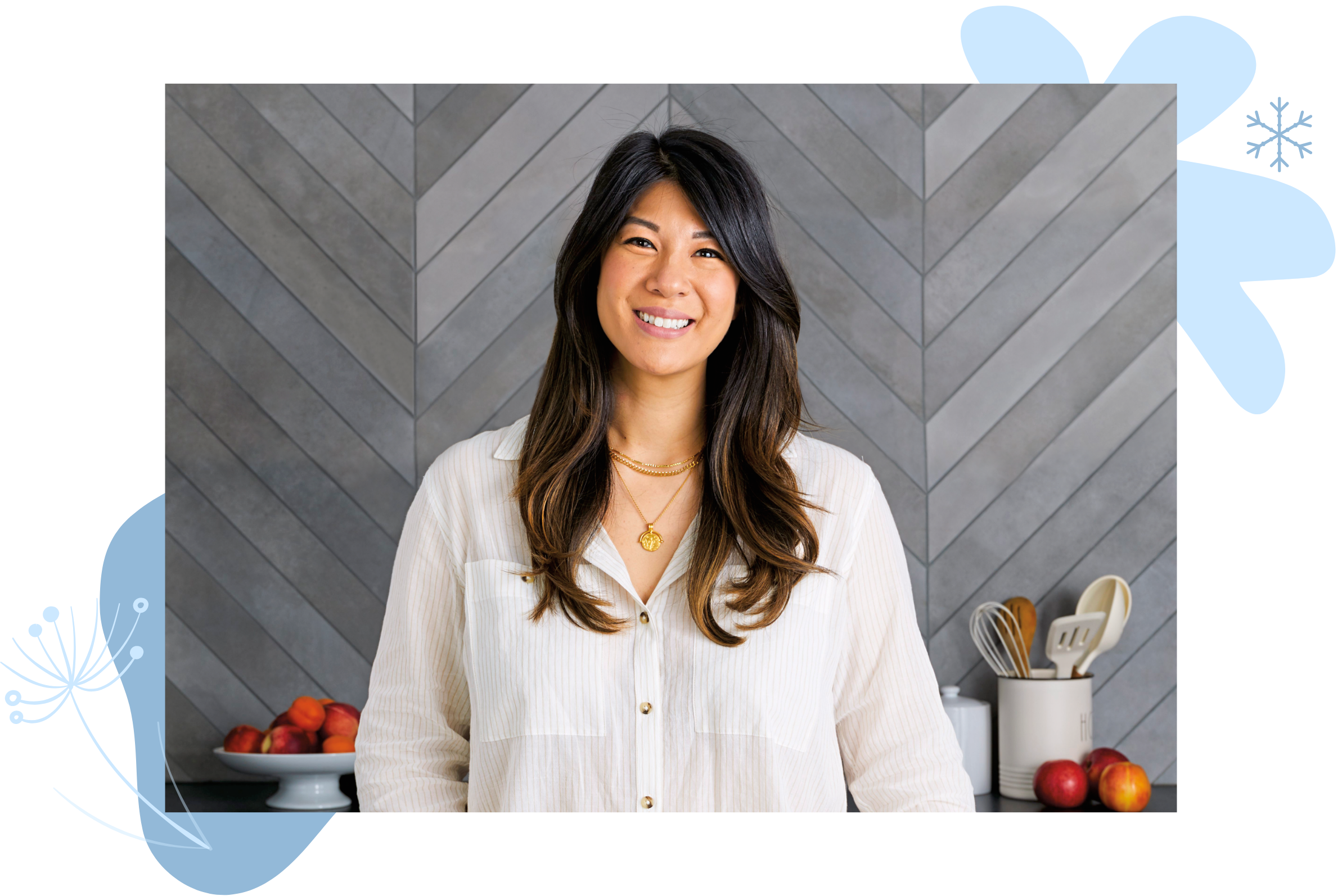 WW Food Director Sherry Rujikarn, wearing a white shirt, standing in front of a gray wall with a plate of fruit and a jar of kitchen tools.