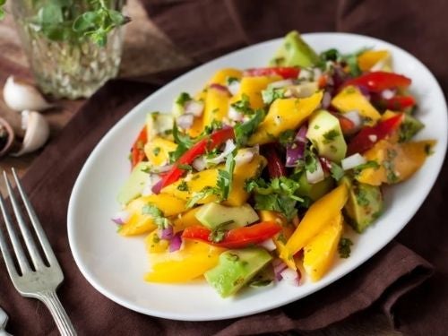 salada tropical com manga e abacate em um prato, com um garfo ao lado