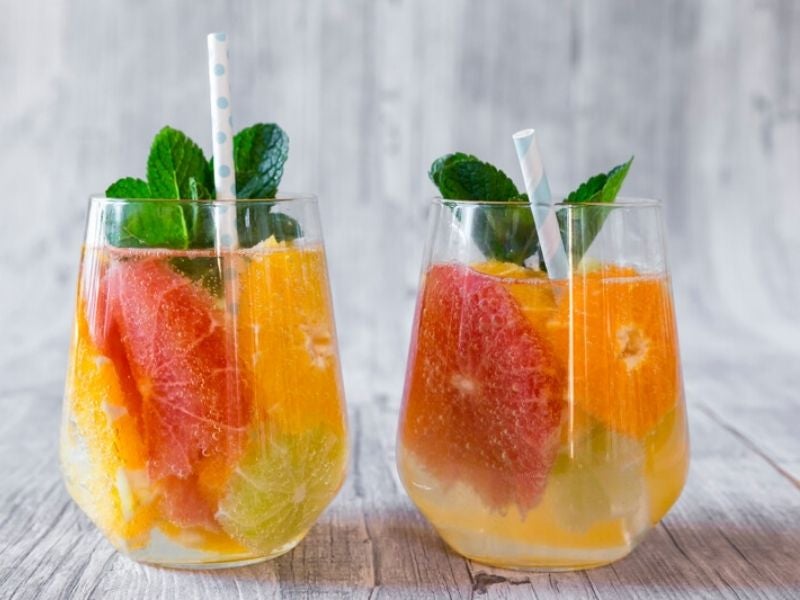 dois copos com frutas cítricas, como laranja, limão e kiwi