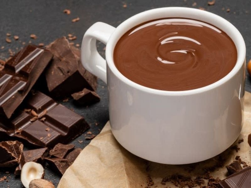 xícara de chocolate quente com barras de chocolate amargo ao lado