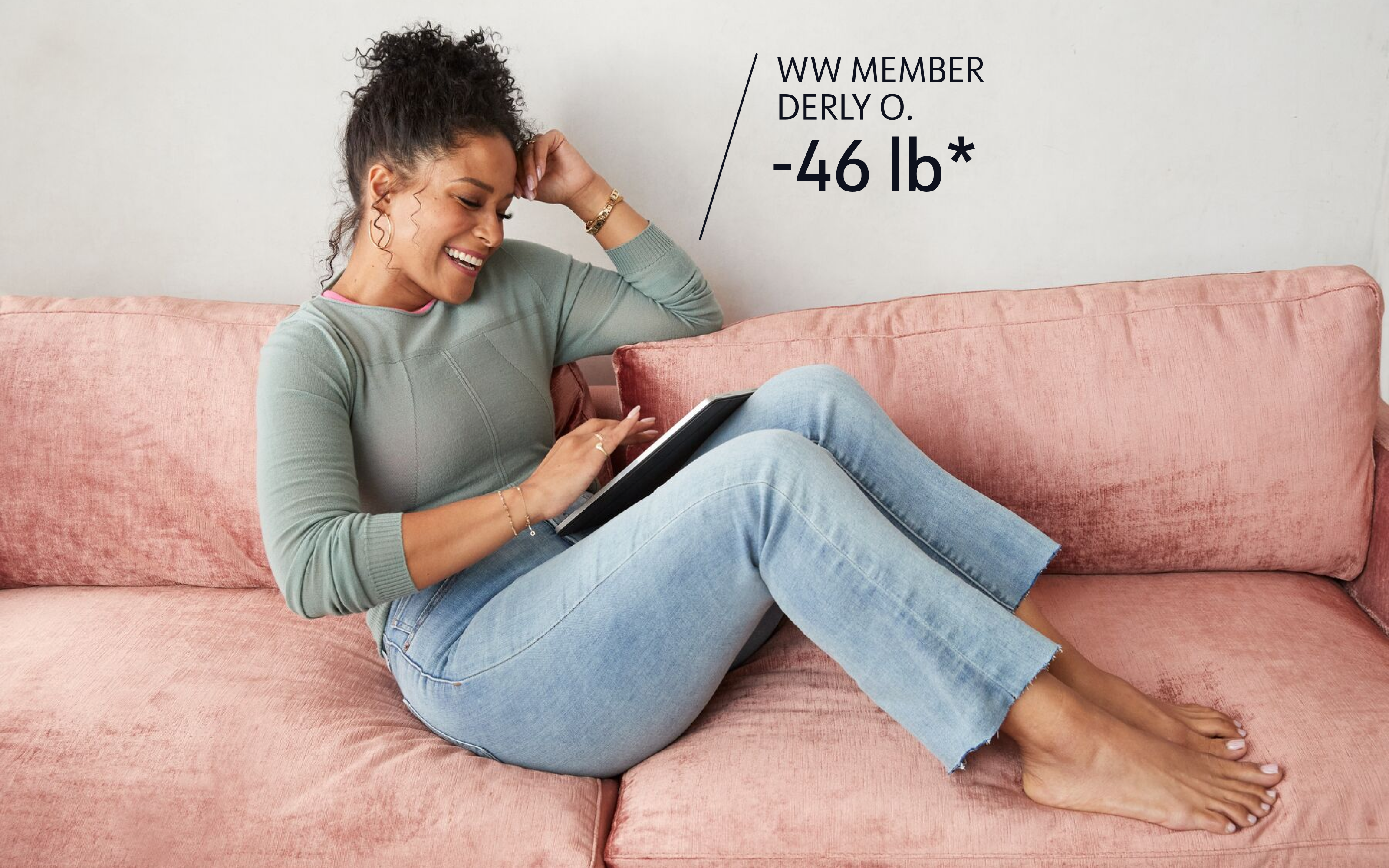 WW member Derly O. has lost 46 pounds. She is relaxing on a couch and looking at her tablet device.