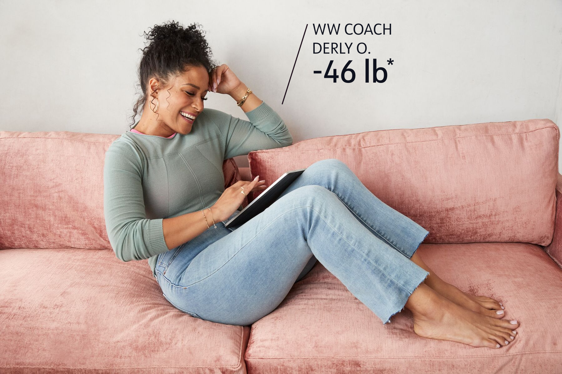 WW Coach Derly O. has lost 46 pounds. She is relaxing on a couch and looking at her tablet device.