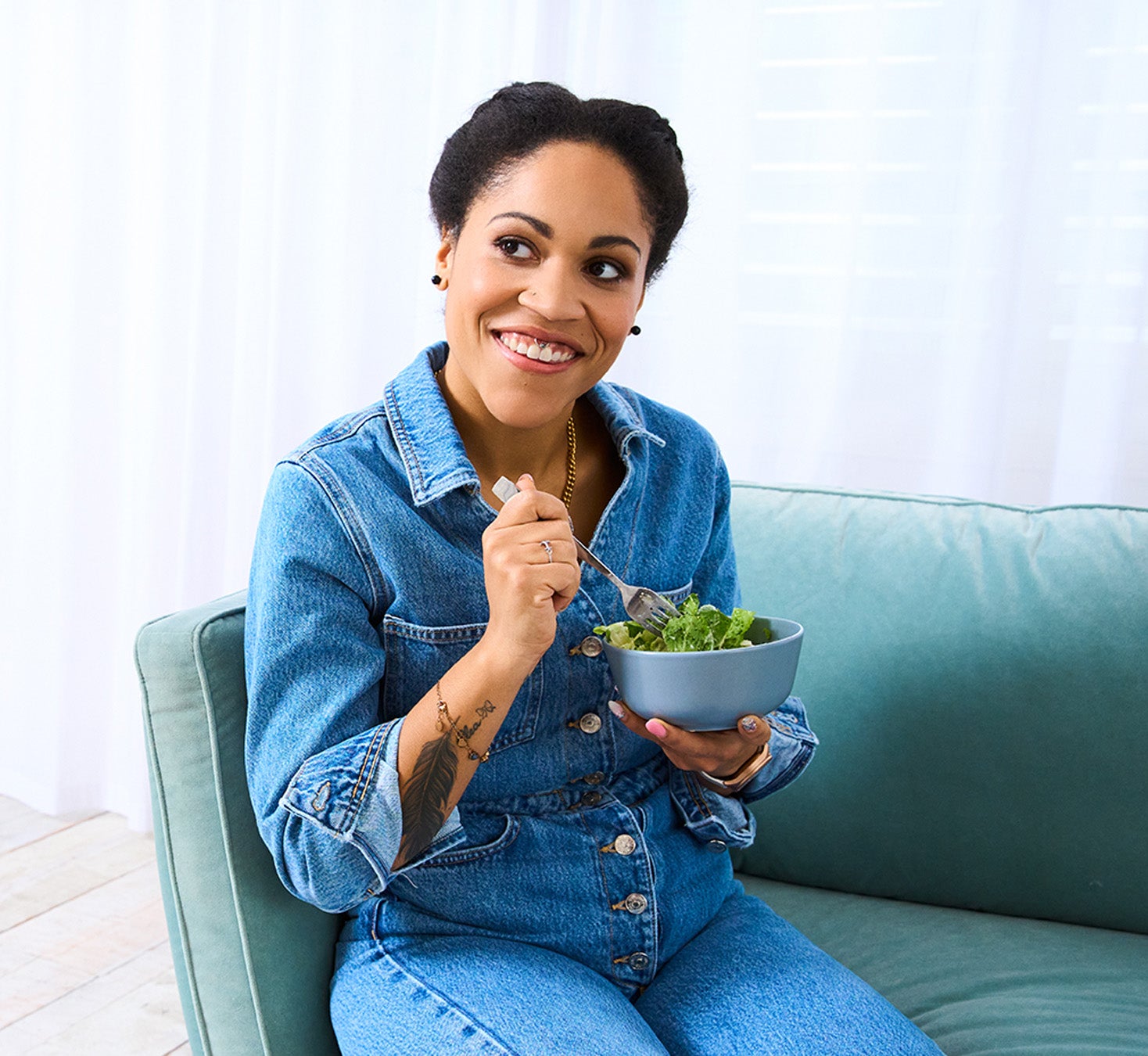 Junge Frau in Jeansoverall isst Salat